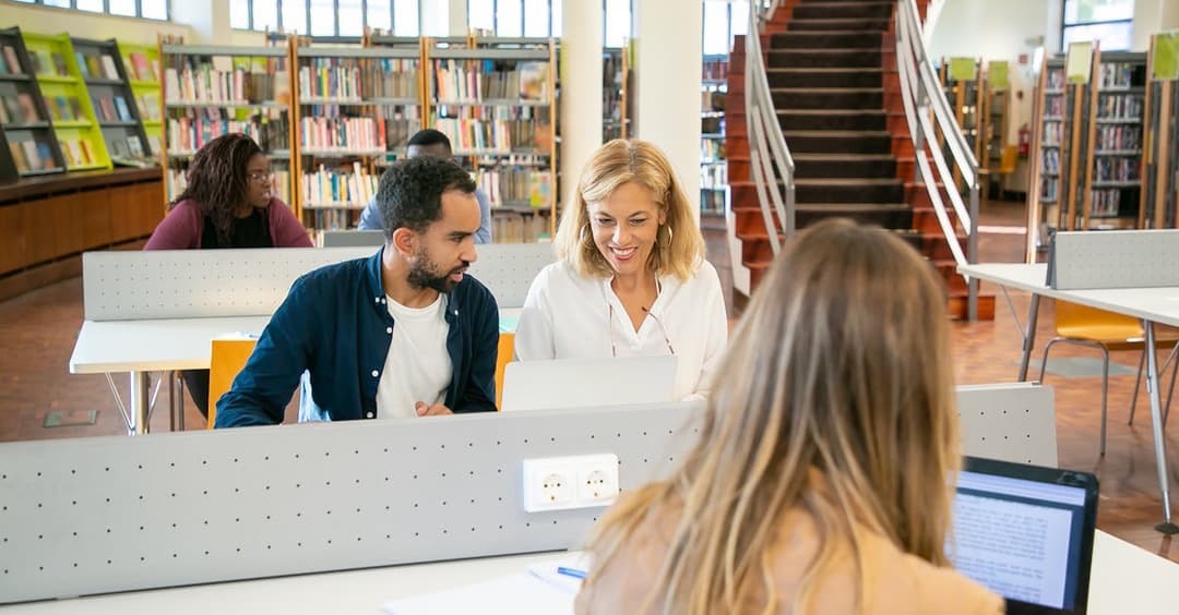 Young students preparing for exams using laptops in library